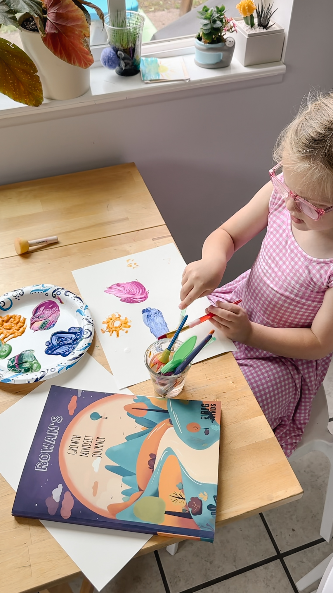Girl painting at table next to her personalized book