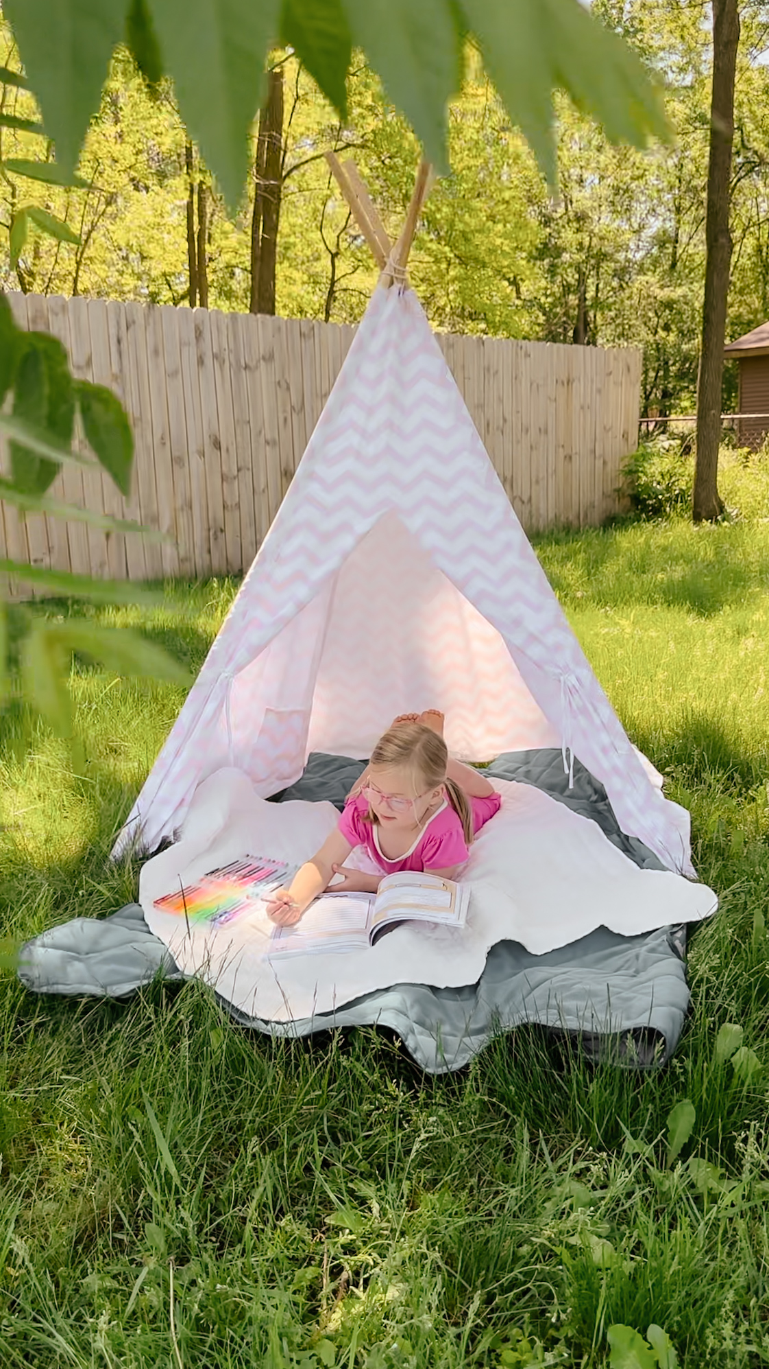 Girl reading in pink teepee in sunny backyard